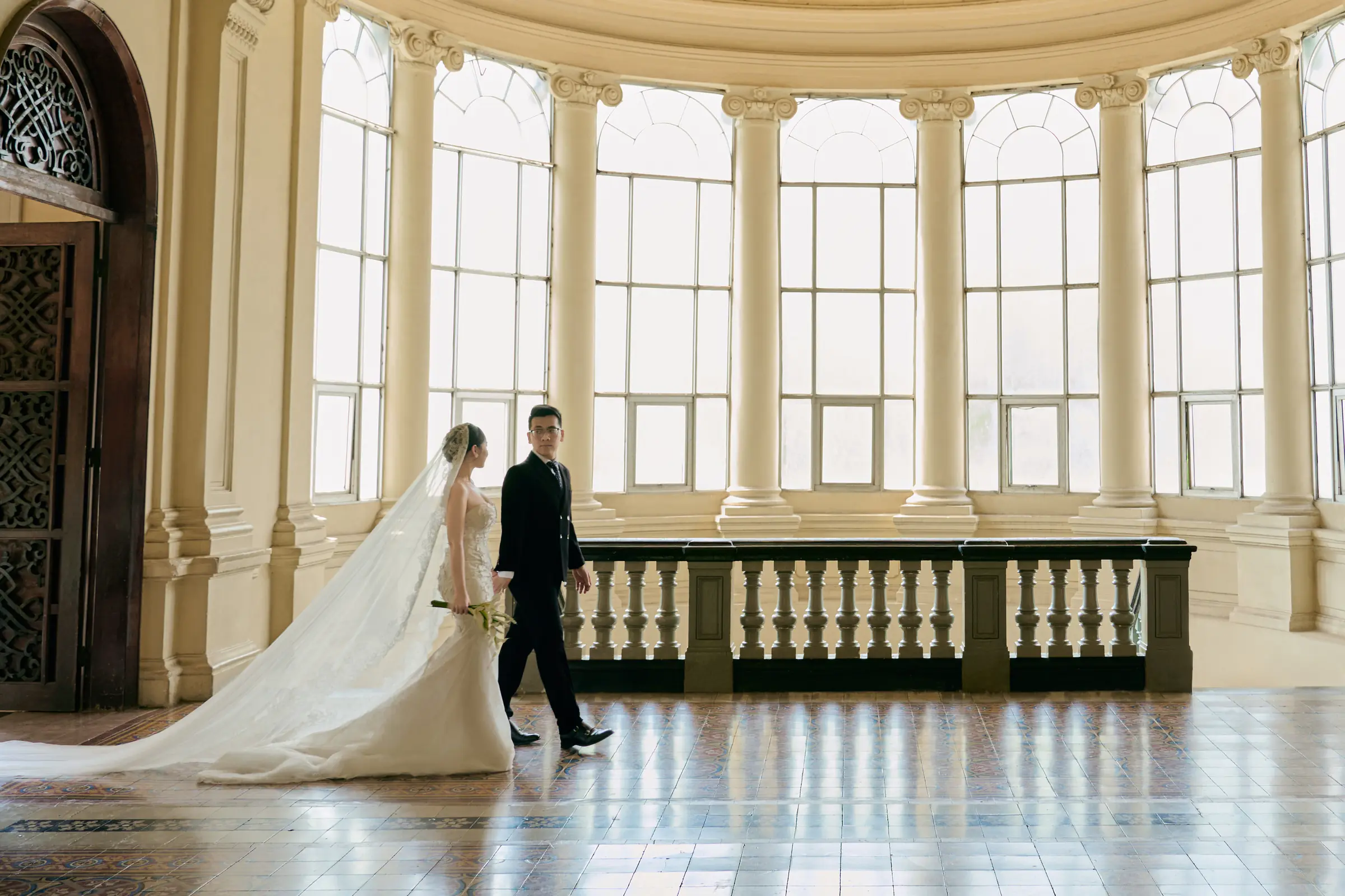 Beyond the doors: the couple walking through the colonnaded rotunda of a heritage palace