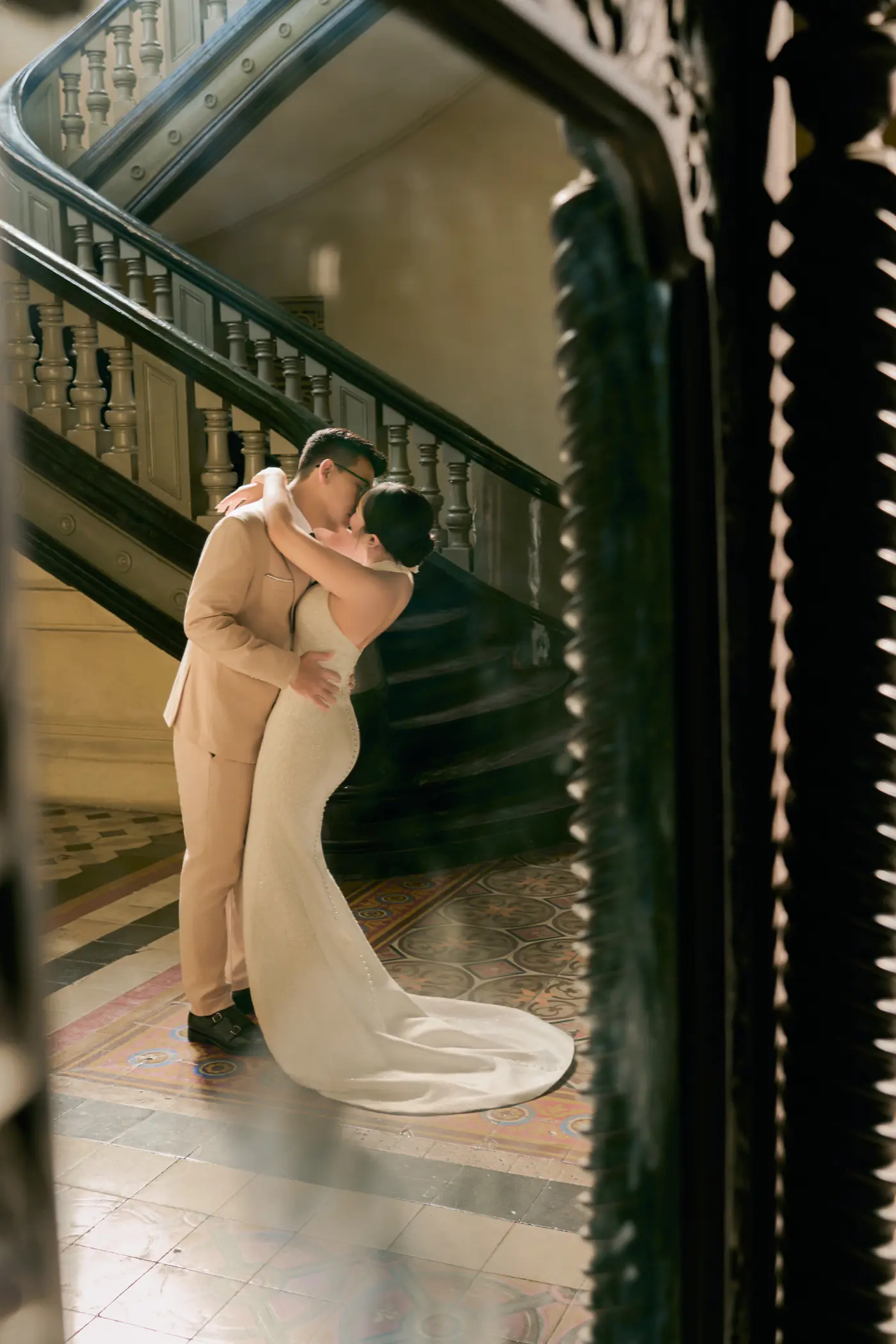 A kiss at the turn of the staircase, framed by a carved mirror