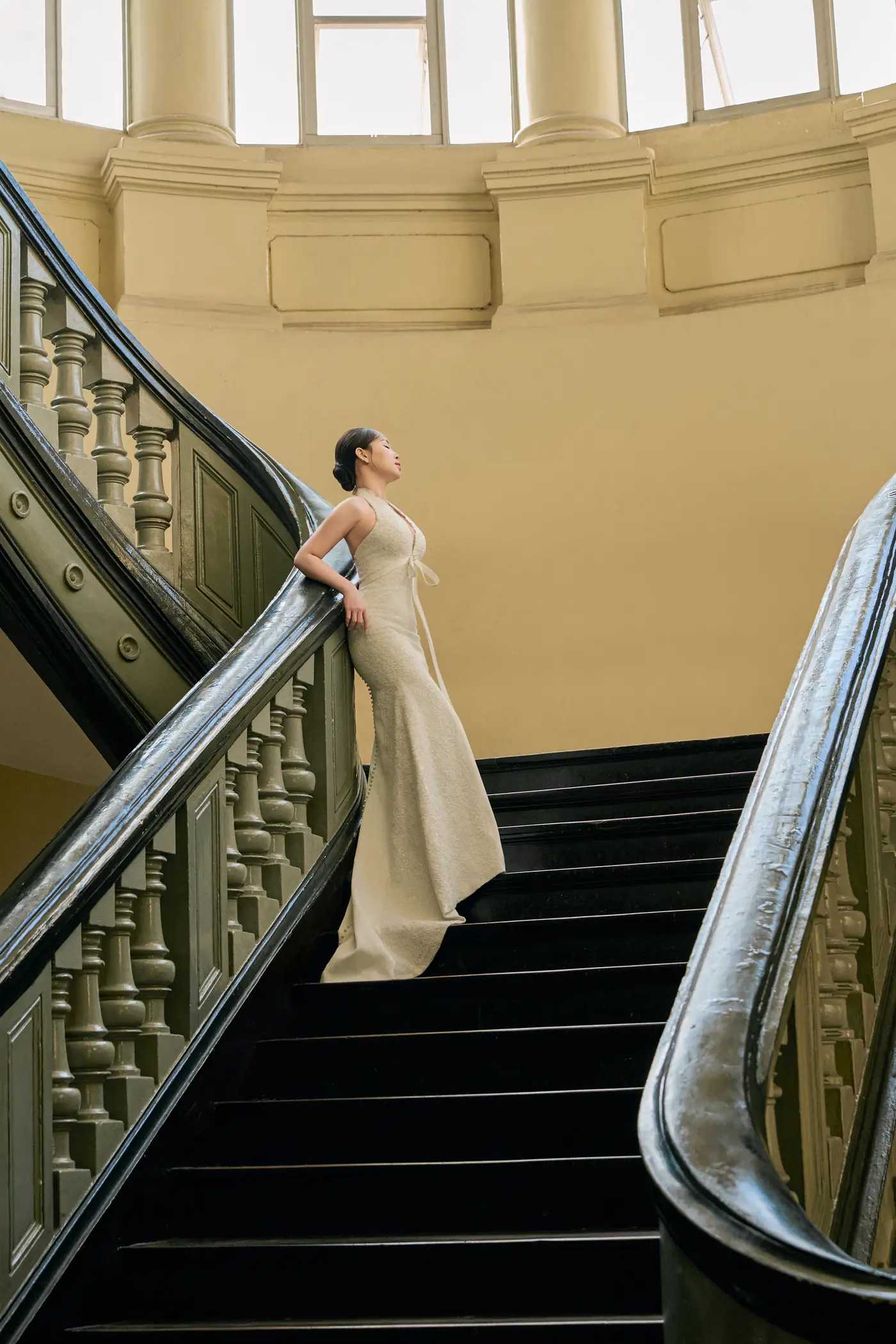 She waits alone on the grand staircase, looking up