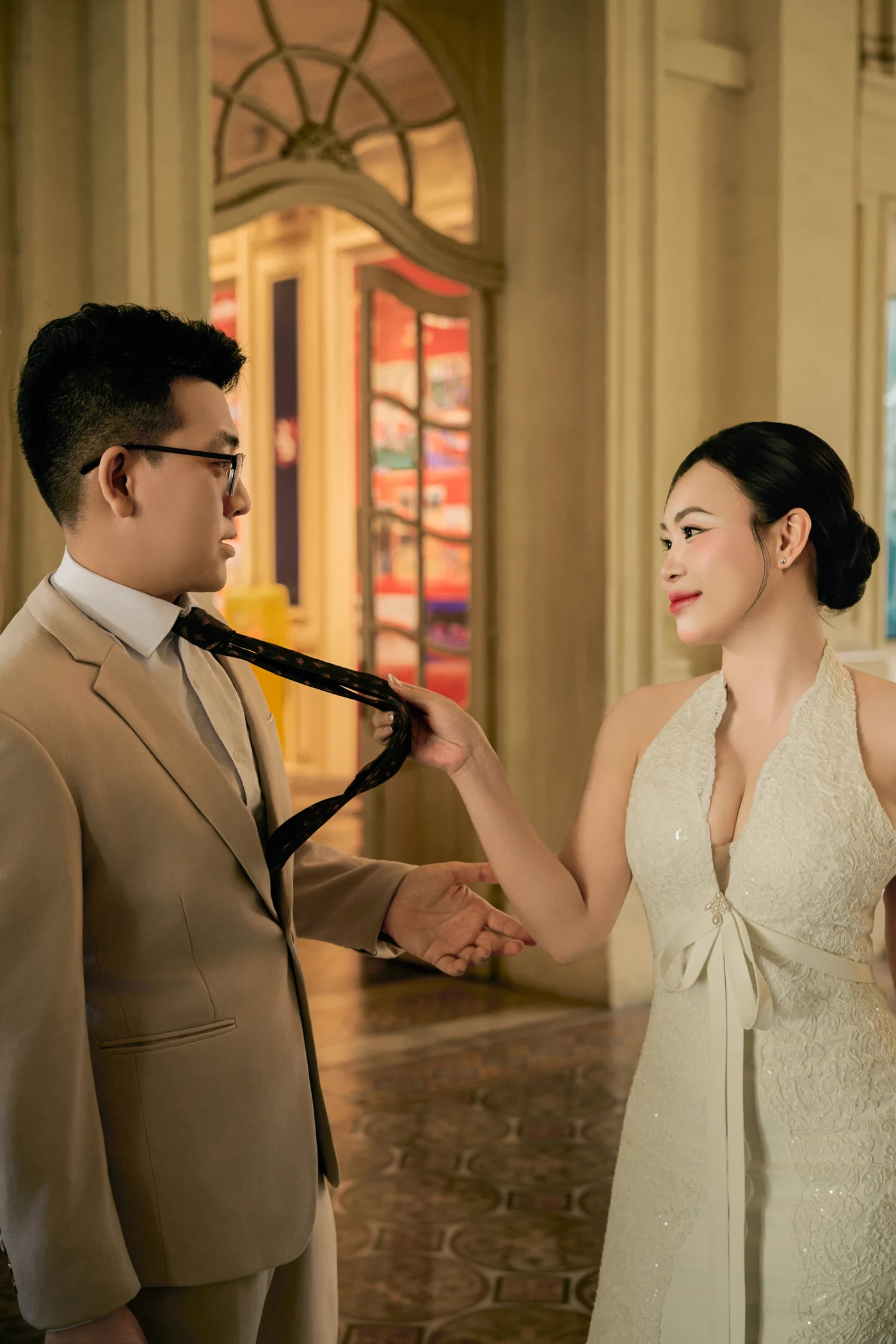 She pulls him in by his tie, both smiling